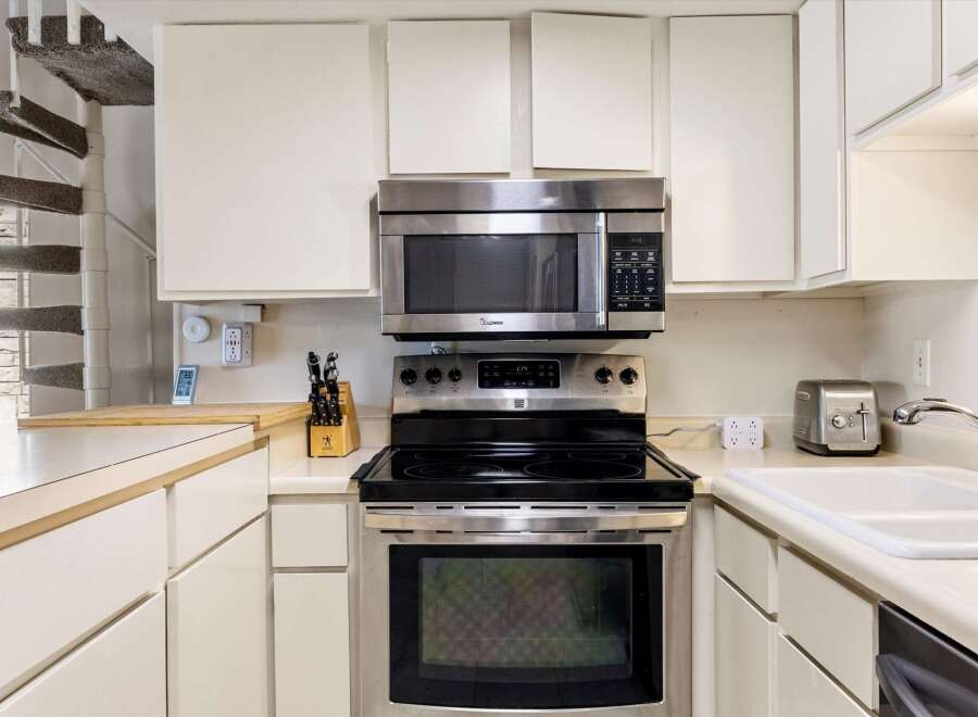 Discover this charming kitchen featuring a sleek stainless steel range and microwave, perfect for culinary adventures.