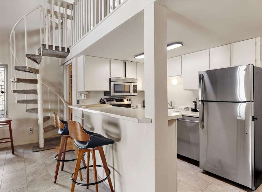 This charming kitchen features a sleek stainless steel refrigerator and a microwave above the stove.