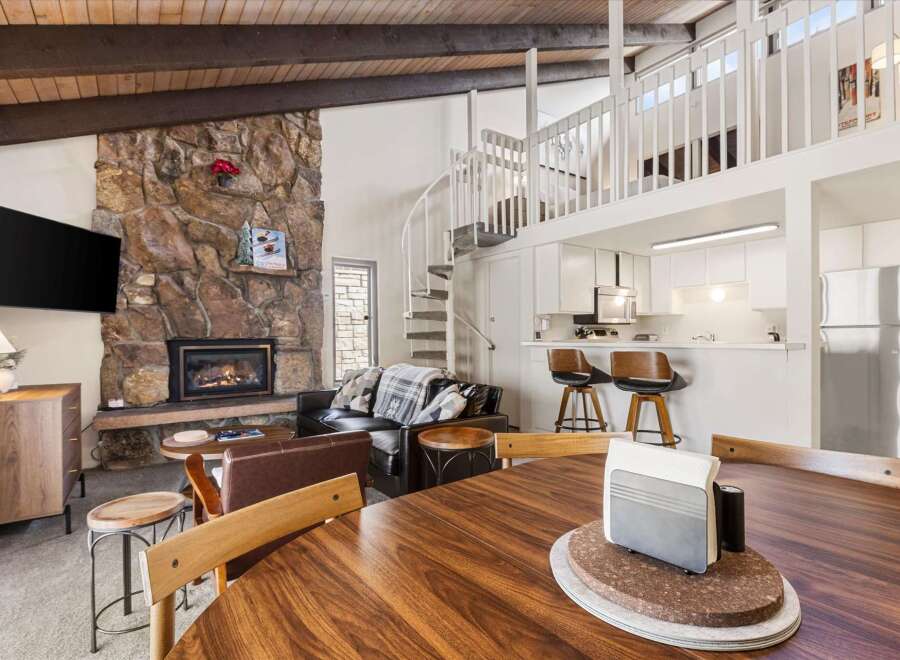 Experience cozy mountain living in this charming condo featuring a stunning stone fireplace and a spiral staircase leading to a loft.