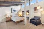 Experience the charm of this unique bedroom featuring a vaulted ceiling with exposed beams and large windows that flood the space with natural light.