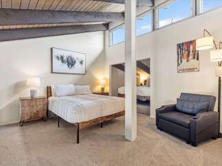 Experience the charm of this unique bedroom featuring a vaulted ceiling with exposed beams and large windows that flood the space with natural light.