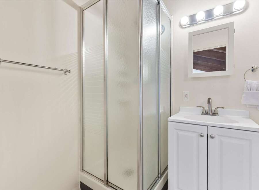 This bathroom features a spacious corner shower with frosted glass doors, perfect for privacy.