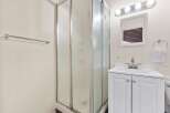 This bathroom features a spacious corner shower with frosted glass doors, perfect for privacy.