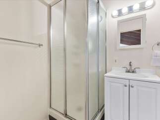 This bathroom features a spacious corner shower with frosted glass doors, perfect for privacy.