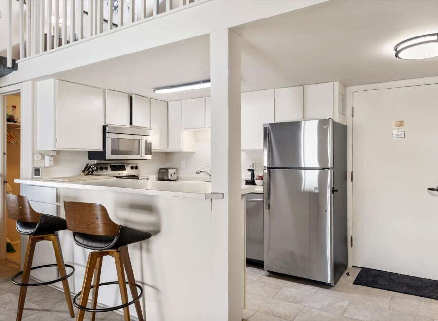 This charming kitchen features a sleek stainless steel refrigerator and a microwave oven above the stovetop.