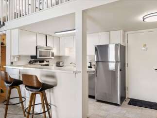 This charming kitchen features a sleek stainless steel refrigerator and a microwave oven above the stovetop.