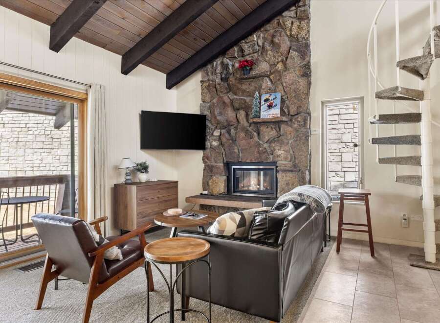 Cozy living room featuring a striking stone fireplace and a large flat-screen TV.