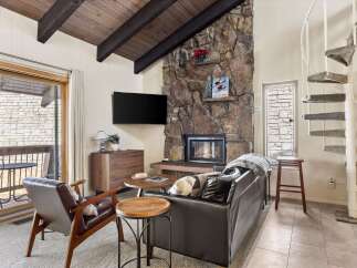 Cozy living room featuring a striking stone fireplace and a large flat-screen TV.