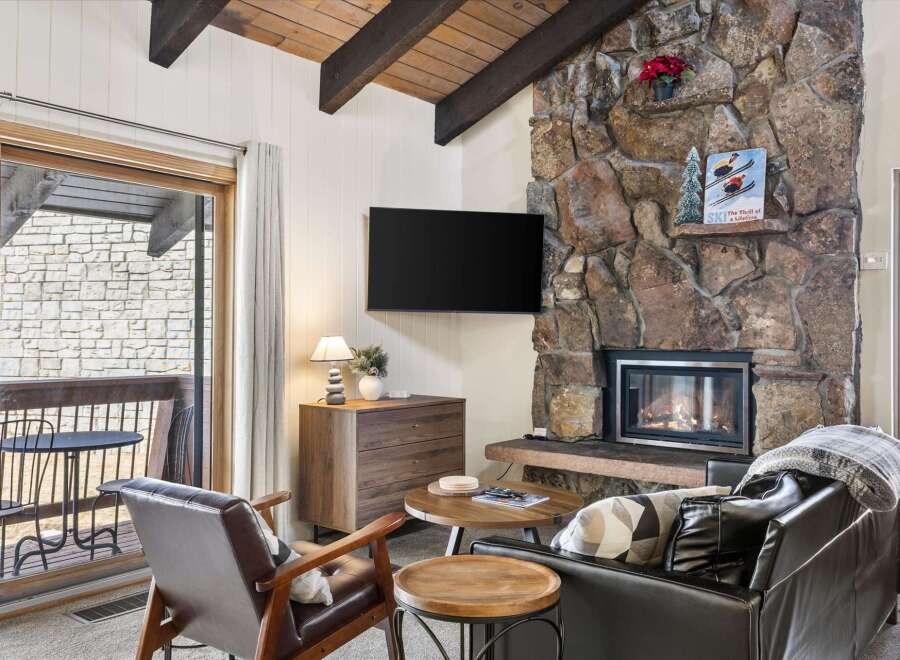 Cozy up by the stunning stone fireplace in this inviting living room, perfect for relaxing after a day on the slopes.