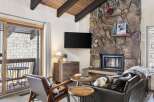 Cozy up by the stunning stone fireplace in this inviting living room, perfect for relaxing after a day on the slopes.