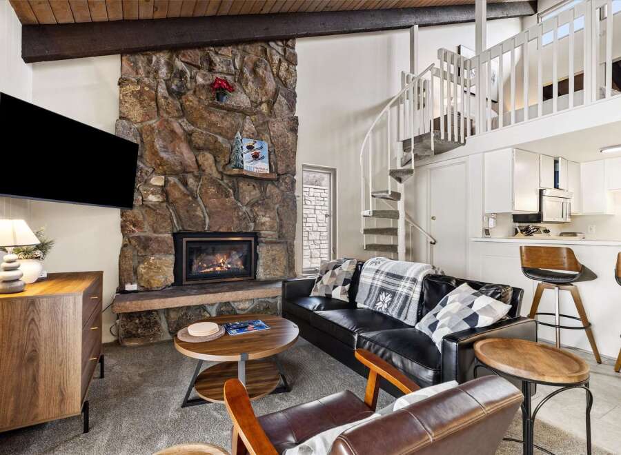 Cozy living room featuring a large stone fireplace and a mounted TV, perfect for relaxing evenings.