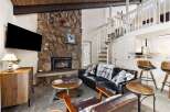 Cozy living room featuring a large stone fireplace and a mounted TV, perfect for relaxing evenings.