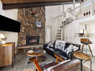 Cozy living room featuring a large stone fireplace and a mounted TV, perfect for relaxing evenings.