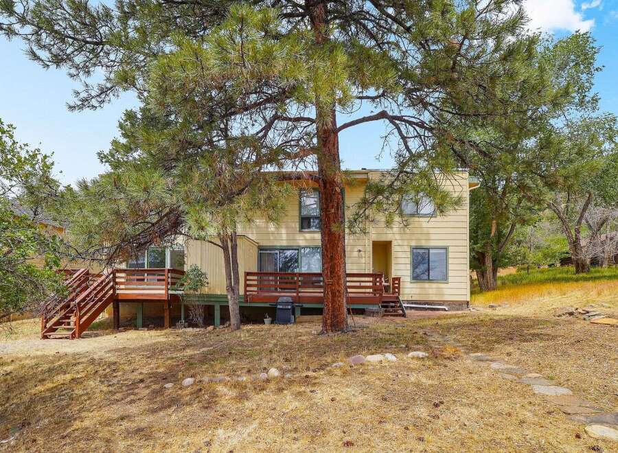 Discover this charming yellow home nestled amongst mature pine trees, offering a serene and private setting.