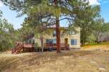 Discover this charming yellow home nestled amongst mature pine trees, offering a serene and private setting.