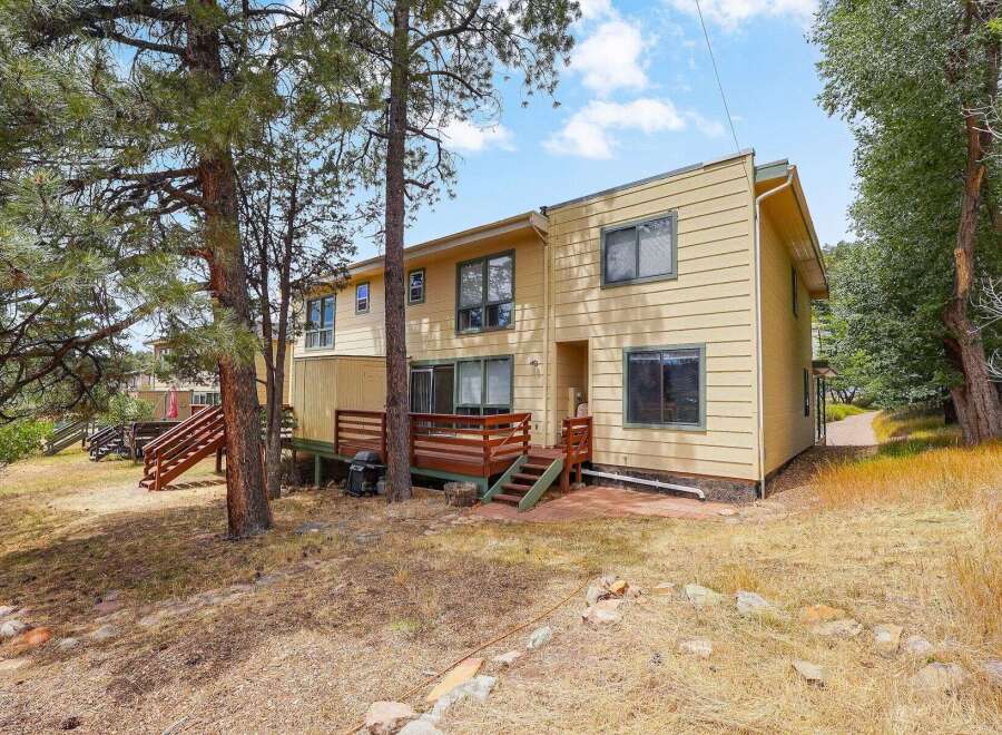 Nestled amongst mature pine trees, this charming yellow home offers a serene retreat.