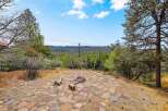 Enjoy breathtaking panoramic views from this stunning property, featuring a natural stone patio and a cozy fire pit perfect for evening gatherings.