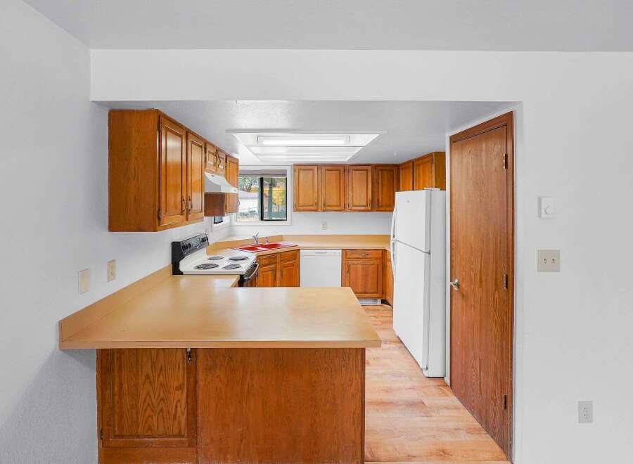 This kitchen features warm wood cabinetry and a spacious countertop, perfect for meal preparation.