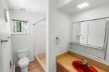 This bathroom features a clean white toilet and a tan bathtub with a textured tile surround.
