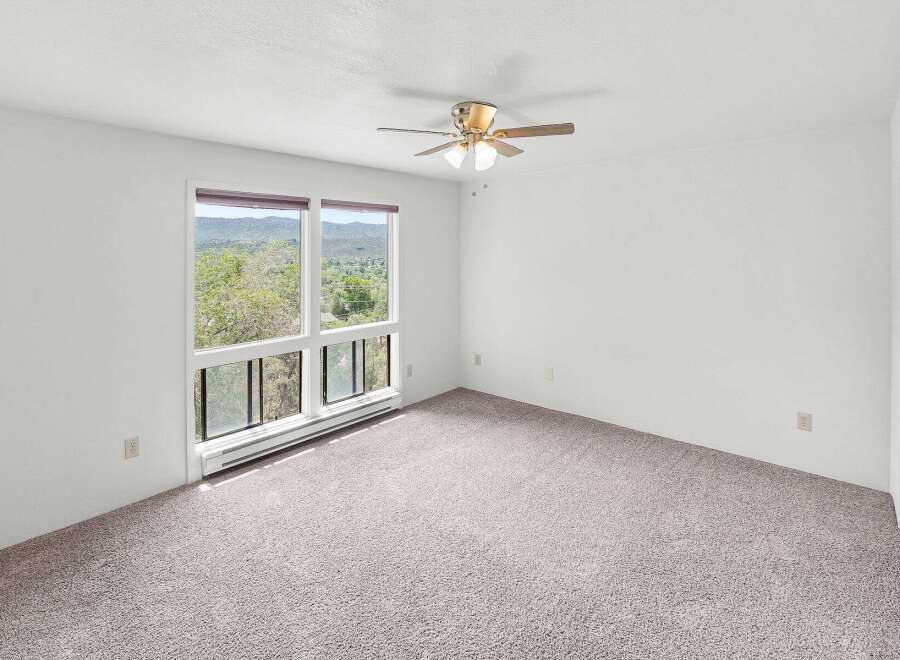 Experience breathtaking views from this spacious bedroom, featuring large windows that frame the picturesque landscape.