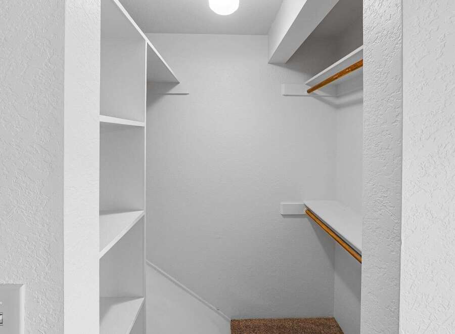Discover ample storage in this walk-in closet, featuring built-in shelving and a convenient hanging rod.