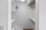 Discover ample storage in this walk-in closet, featuring built-in shelving and a convenient hanging rod.