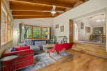 Experience rustic charm in this inviting living space featuring a vaulted wood-beamed ceiling and abundant natural light from large windows.