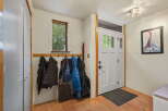 Welcome guests into this charming entryway featuring a wooden coat rack adorned with jackets and a vintage trunk.