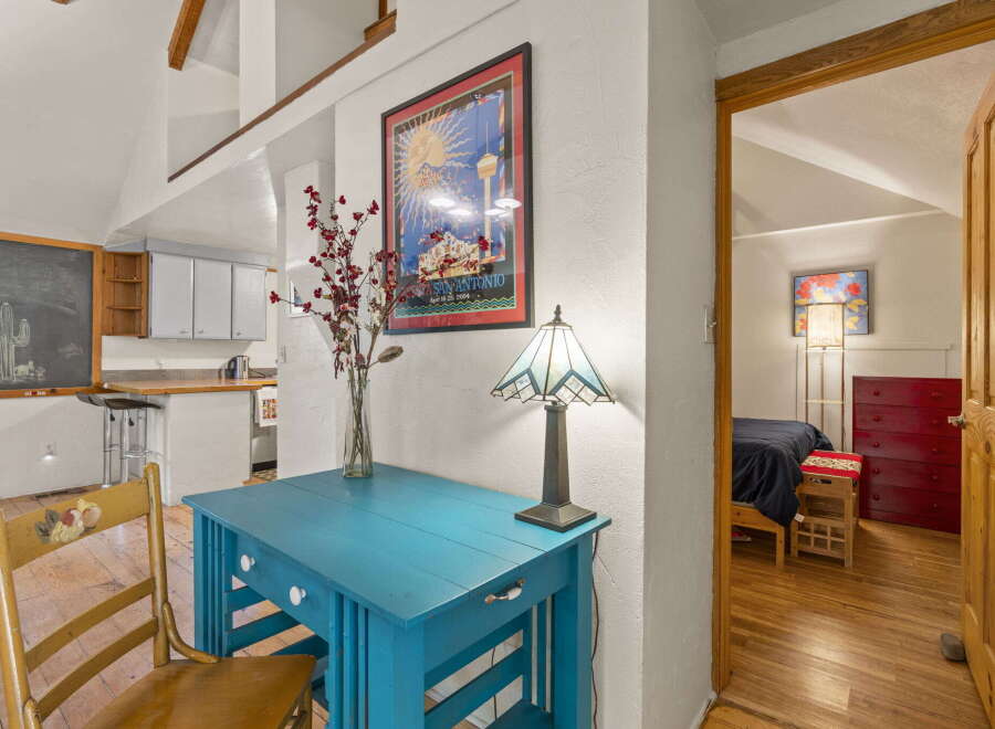 Discover this charming property featuring a bright turquoise desk and a vintage wooden chair, perfect for a cozy workspace.