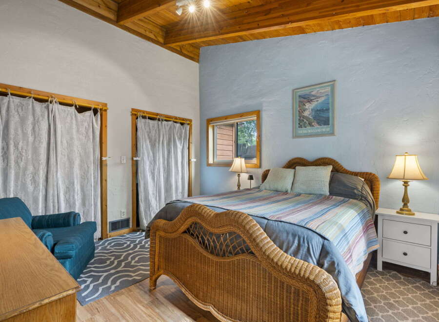 Experience coastal charm in this inviting bedroom featuring a cozy wicker bed and a serene blue accent wall.