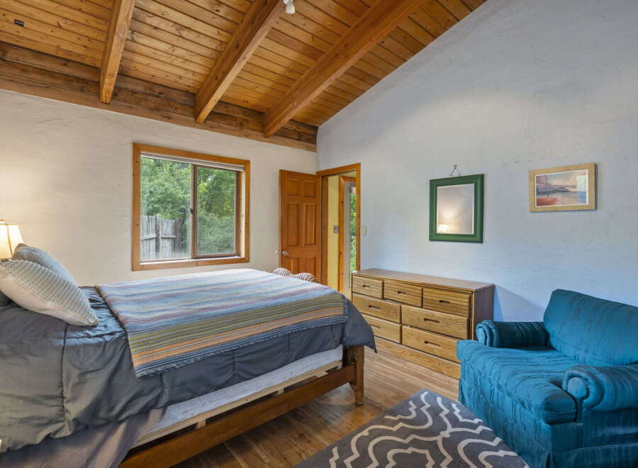 This charming bedroom features a cozy bed with a colorful striped blanket, perfect for relaxation.