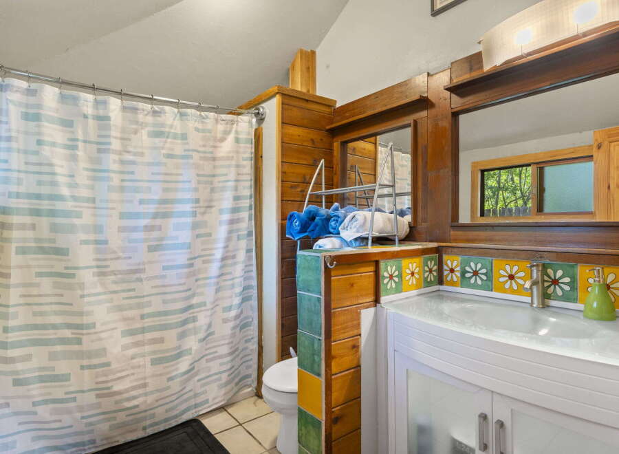 This charming bathroom features a unique wooden vanity with a decorative tile backsplash showcasing floral patterns.