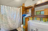 This charming bathroom features a unique wooden vanity with a decorative tile backsplash showcasing floral patterns.