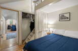 Discover this cozy bedroom featuring a comfortable queen-sized bed with crisp white pillows and a deep blue comforter.