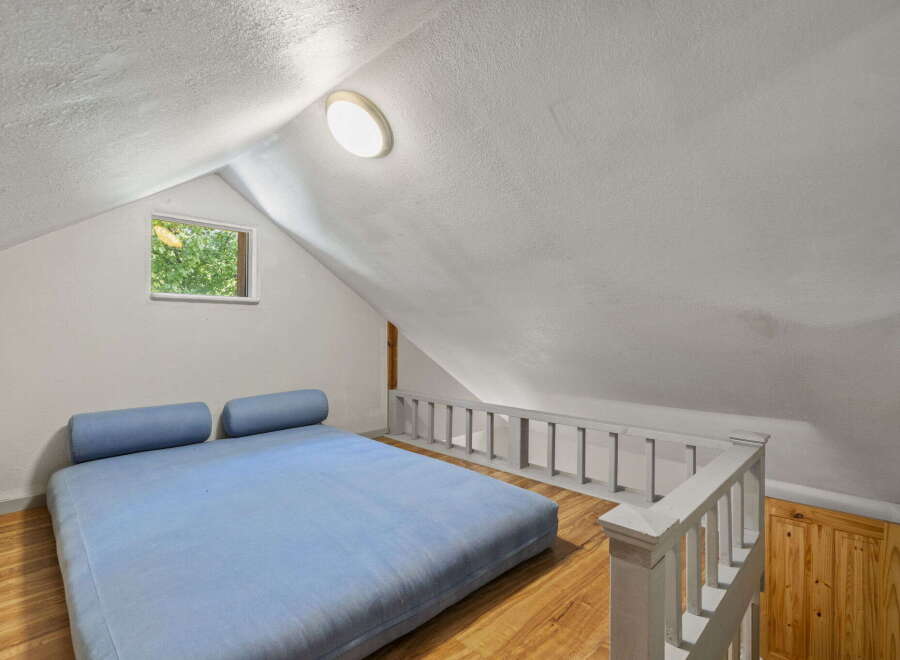 Discover this charming loft bedroom, featuring a comfortable blue futon and two bolster pillows, perfect for relaxation.