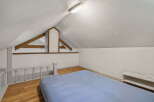 Discover this charming attic bedroom, featuring a cozy blue mattress laid directly on the wooden floor.