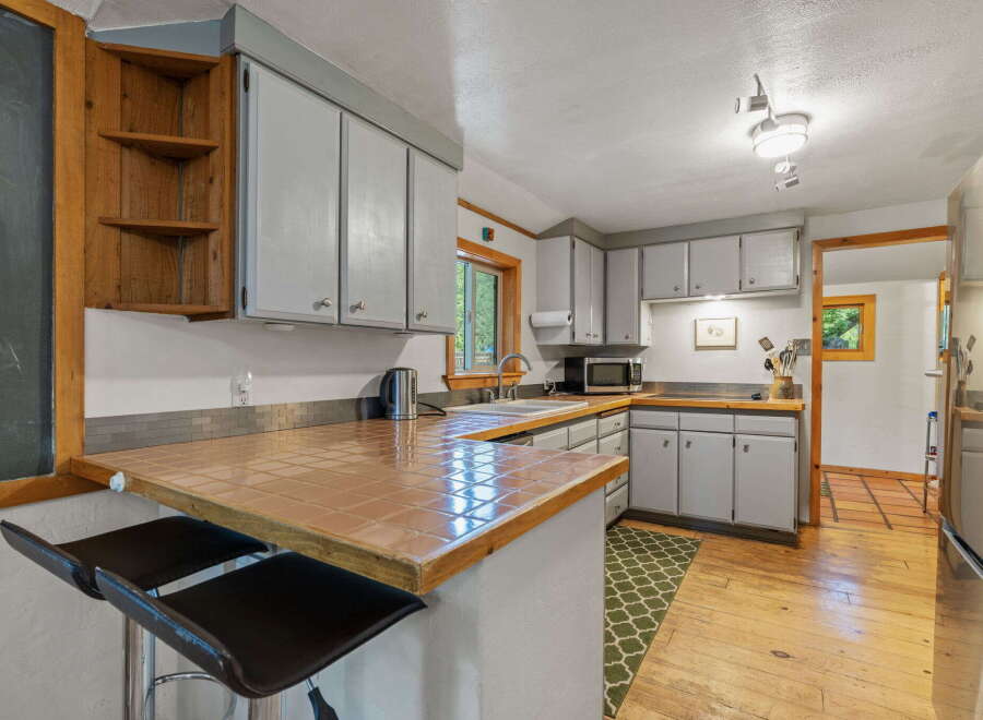 Discover this charming kitchen featuring a unique tiled countertop and a built-in wooden shelf unit, perfect for storage and display.