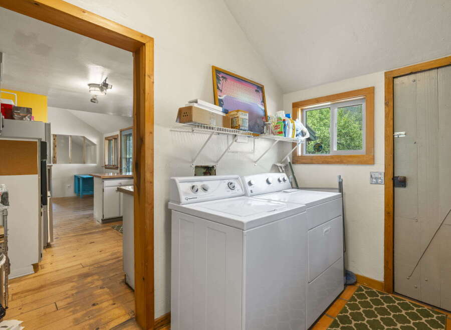This charming laundry room features a white top-loading washer and dryer set, perfect for handling household chores.