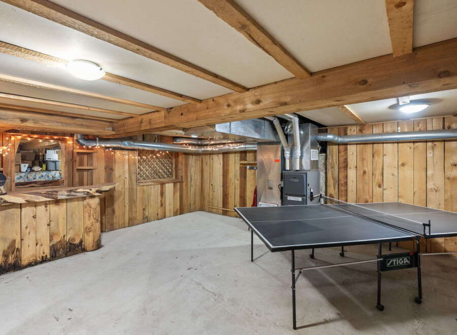 This rustic basement features a custom-built wooden bar area, perfect for entertaining guests.
