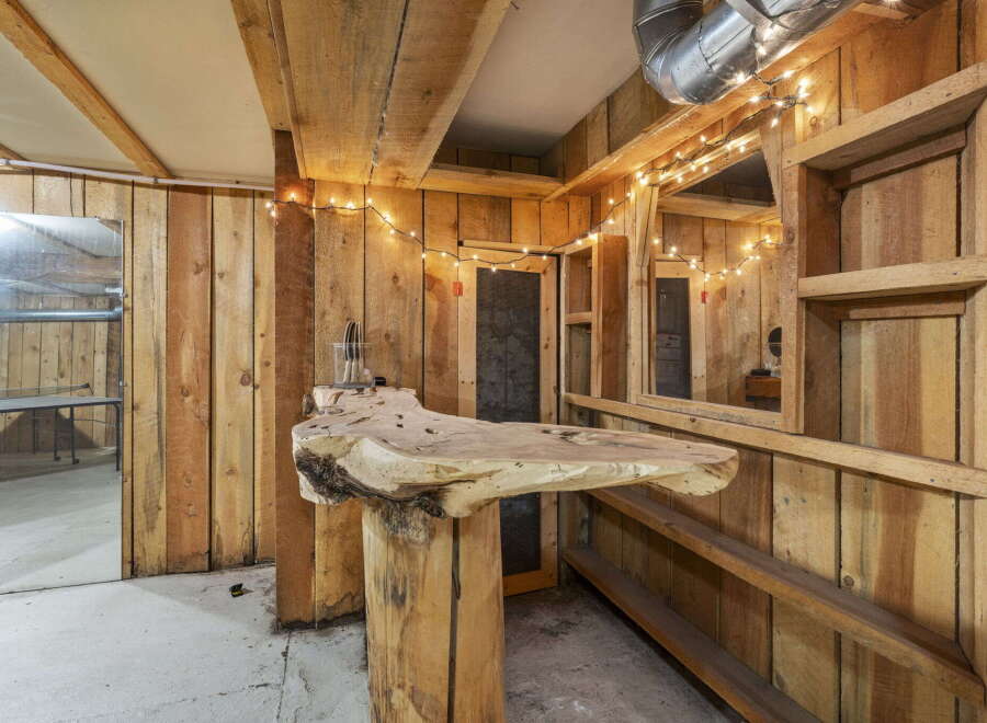 Discover a unique rustic bar area, perfect for entertaining, featuring a live-edge wood countertop supported by a substantial log base.