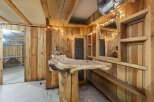 Discover a unique rustic bar area, perfect for entertaining, featuring a live-edge wood countertop supported by a substantial log base.