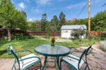 Enjoy outdoor living in this charming backyard featuring a paved patio area with a glass-top table and chairs, perfect for al fresco dining.