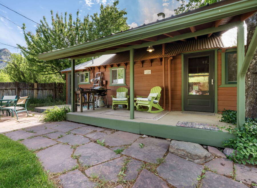 Enjoy outdoor living with a covered porch featuring two charming green chairs, perfect for relaxing.