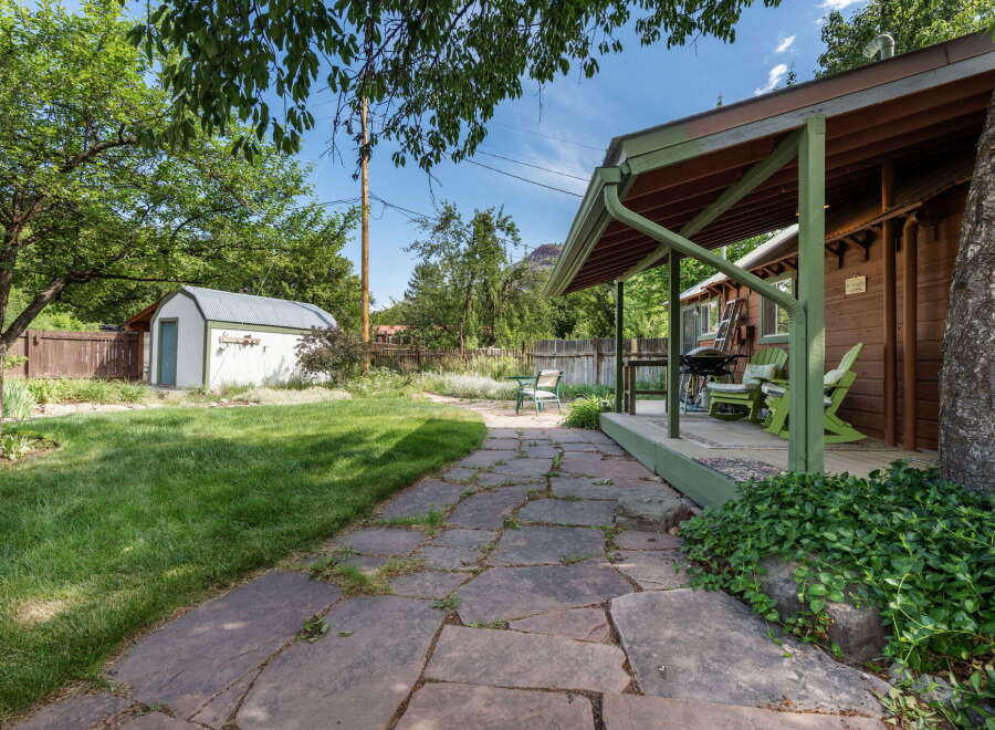 Enjoy outdoor living in this charming backyard featuring a covered porch with seating and a grill, perfect for entertaining.