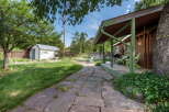 Enjoy outdoor living in this charming backyard featuring a covered porch with seating and a grill, perfect for entertaining.