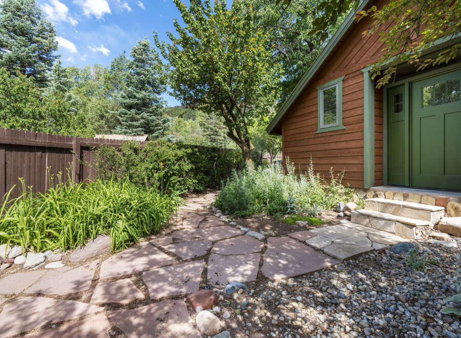 Discover a charming backyard oasis featuring a rustic wooden cabin with a vibrant green door and window trim.