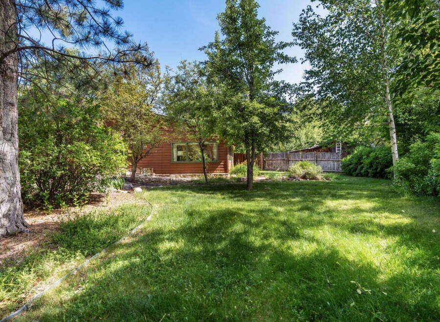 Discover this charming home nestled amidst lush greenery and mature trees, offering a serene backyard oasis.