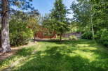 Discover this charming home nestled amidst lush greenery and mature trees, offering a serene backyard oasis.