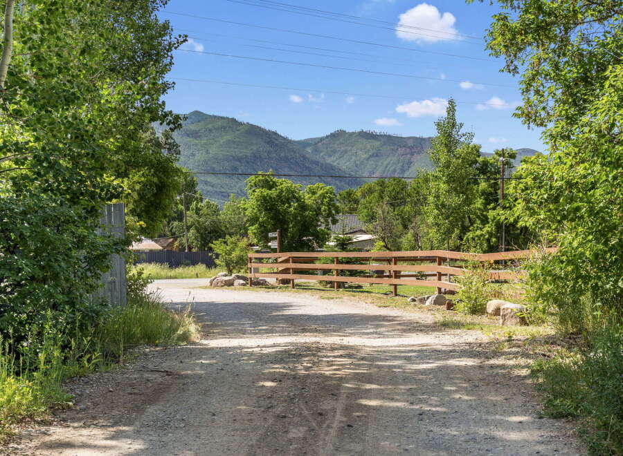 Discover this charming property with a picturesque setting, featuring a rustic wooden fence and lush green trees.