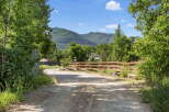 Discover this charming property with a picturesque setting, featuring a rustic wooden fence and lush green trees.
